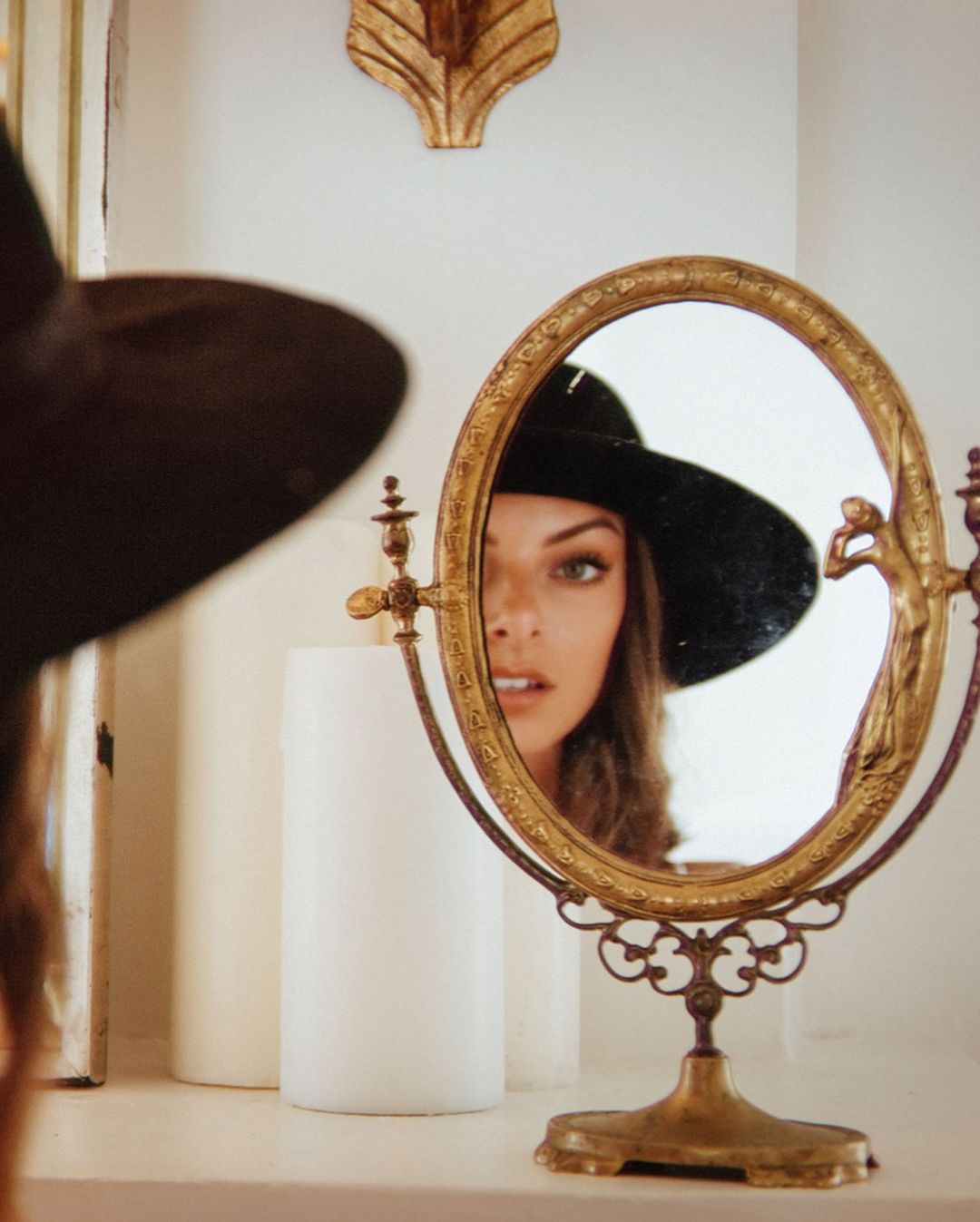 Jessica is wearing a hat in front of the mirror