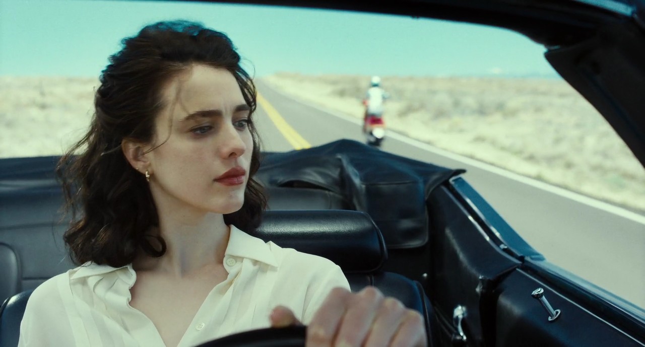 Honey O'Donahue (Margaret Qualley) driving a Chevy Chevelle looks in the rearview mirror at a scooter