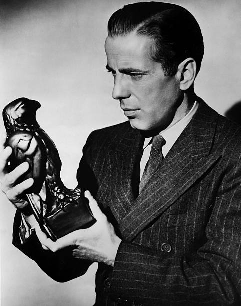 Humphrey Bogart holds a Maltese Falcon statuette, a promo photo for the 1941 film noir
