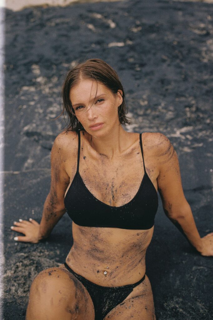 Naila May, a girl in a black bikini on black sand
